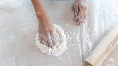 Genç çekici Asyalı kız, tatilde öğle yemeği için mutfağında ekmek yapmak için ahşap silindiri ya da harman makinesini alır.