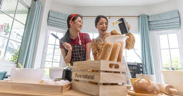 若い女性が台所で一緒に働いている家庭でパン作りをしています エプロンをしたある女性は 家で新鮮なパンを作る方法を友人に教えています — ストック写真