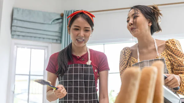 若い女性が台所で一緒に働いている家庭でパン作りをしています エプロンをしたある女性は 家で新鮮なパンを作る方法を友人に教えています — ストック写真
