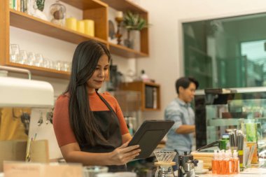 Genç bayan girişimci, e-marketini geliştirmek için dizüstü bilgisayar kullanıyor. İş kadını, dükkanını tanıtmak için dijital cihaz kullanarak evrak işlerini değiştiriyor. İş hayatında uygulama veya yazılım kullanımı