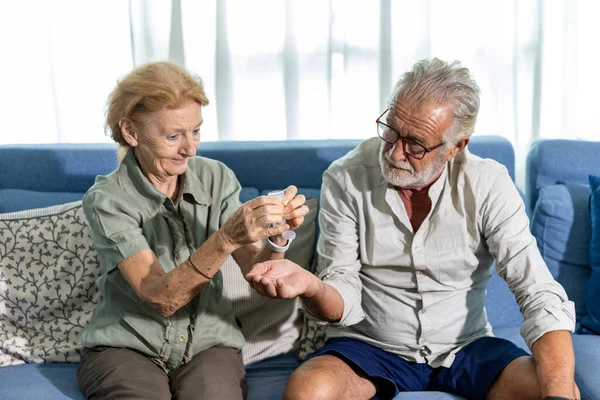 Senior couple use alcohol gel to clean their hands as part of new normal preventing COVID-19 infection. Elderly adults in quarantine at home washing hands with alcohol sanitizer