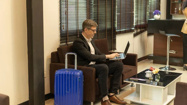 Male business traveler using airport lounge or lobby to prepare for his trip. Business man is checking online information while waiting for his flight in a VIP room
