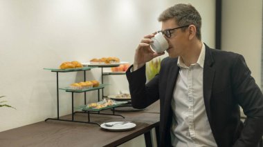 Young business man uses computer notebook to work with his colleagues at a coffee counter. Male officer works with his laptop in a coworking space.