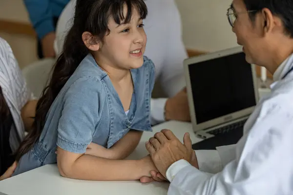A girl gets good care from a male doctor by holding his hand with feeling good and listening the result from her diagnosis. Doctor takes care his patient with warm hospitality.