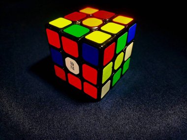 Siyah arkaplana karşı bir Rubik Küpü, üç boyutlu bir perspektifte resmedilmiş.
