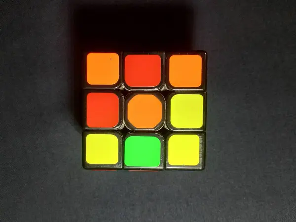 Yukarıdan bakıldığında, simsiyah bir arkaplan karşısında duran bir Rubik Küpü.