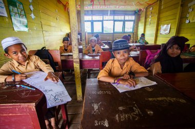 İlkokul öğrencileri Endonezya 'nın Barito Kuala kasabasında geleneksel bir sınıfta birlikte okuyorlardı..