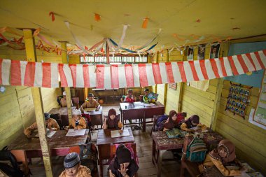 İlkokul öğrencileri Endonezya 'nın Barito Kuala kasabasında geleneksel bir sınıfta birlikte okuyorlardı..