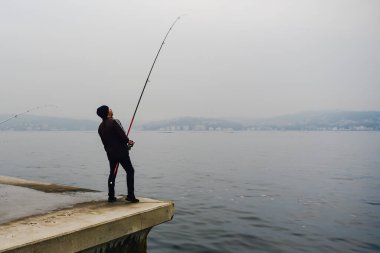 Türkiye 'nin İstanbul kenti - 14 Kasım 2019: Sisli havada sahilde balık tutan yetişkinler. Yüksek kalite fotoğraf