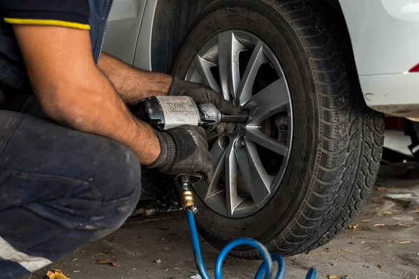 stock image Auto mechanic man with electric screwdriver changing tire outside. Car service. Tire installation concept. High quality photo