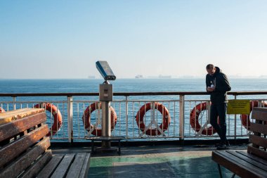 İstanbul, Türkiye Kasım 12022: feribotta seyahat eden genç adam, telefonuna bakıyor. Yüksek kalite fotoğraf