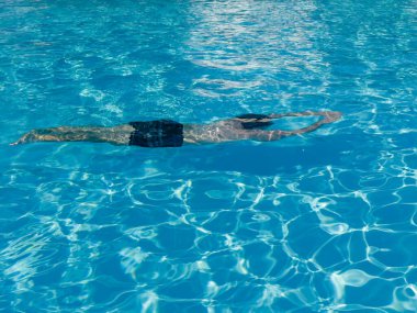 Havuzda yüzen küçük bir çocuk, havuzun içinde suyun altında hareket ediyor. Yüksek kalite fotoğraf