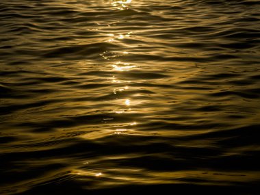 Gün batımında denizde oluşan soyut dalgalar, sarı siyah günbatımı arka planı. Yüksek kalite fotoğraf