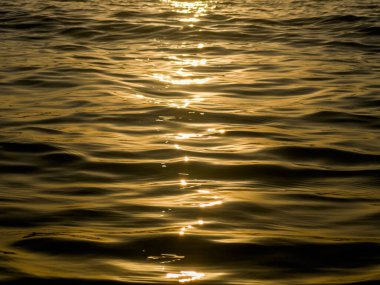 Gün batımında denizde oluşan soyut dalgalar, sarı siyah günbatımı arka planı. Yüksek kalite fotoğraf