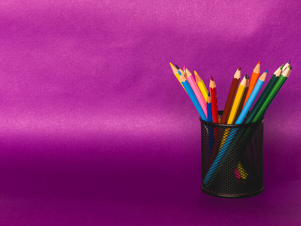 cylinder shaped metal net box pencil holder isolated on yellow background. many colored pen , education concept , copy space area. High quality photo