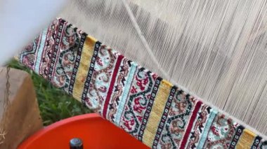 Halı dokuma tezgahında geleneksel teknikler kullanılıyor. Dokuma ve el yapımı halı üretimine yakın plan..
