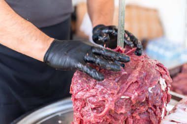 Usta Türk kebabını kırmızı etten pişirmeye hazırlıyor, pişmemiş donör kebap eti, Yunan jiroskopu bir restoranda tükürükte. Yüksek kalite fotoğraf