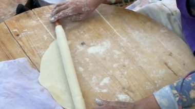 Kadın merdaneli hamuru yuvarlıyor, orta yaşlı kadın geleneksel yöntemlerle hamuru yuvarlıyor, Türk sokak yemekleri