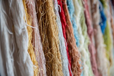 Tekstil fabrikasında dokumak için renkli ipek iplikler, pamuk rengi el yapımı doğal boyalar, eski dokuma tezgahı ve iplik ipliği.. 