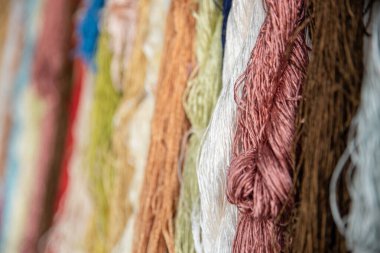 Tekstil fabrikasında dokumak için renkli ipek iplikler, pamuk rengi el yapımı doğal boyalar, eski dokuma tezgahı ve iplik ipliği.. 