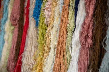 Tekstil fabrikasında dokumak için renkli ipek iplikler, pamuk rengi el yapımı doğal boyalar, eski dokuma tezgahı ve iplik ipliği.. 
