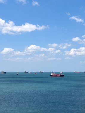 Bulutlu bir günde deniz kenarında bekleyen bir sürü kargo gemisi, deniz taşımacılığı konsepti. 