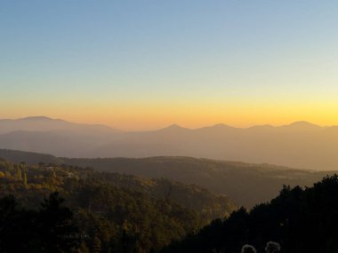 Gecenin erken saatlerinde sakin bir manzarada uzak dağlar ve vadilerin üzerine ılık renkler döküyor. Yüksek kalite fotoğraf