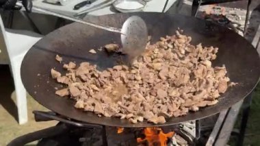 Şef ahşap ateşin üzerinde tavada et yemeği pişiriyor. Geleneksel Türk mutfağı. Yüksek kalite 4k görüntü