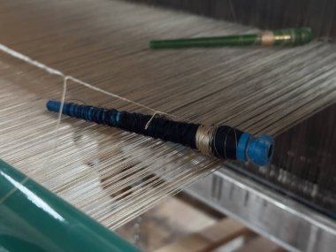 Dokuma, geleneksel el sanatları, dokuma tezgahının yakın çekimi, pamuk ve ipek iplik kullanarak esneme ve dokuma makinesini kullanarak örgü örmek..