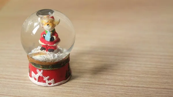 Weihnachten Schneekugel Mit Hirsch Trägt Weihnachtsmanntuch Auf Tisch Nahaufnahme — Stockfoto