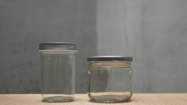 Two empty jars with lid on wooden table