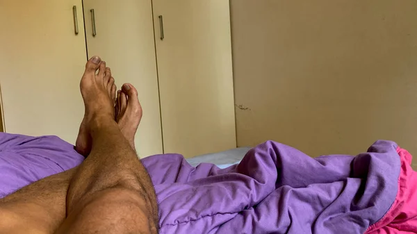 Asian man's leg. Foot Crossover relaxing on bed with white wardrobe on the background