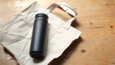 Siyah paslanmaz taklalar ve tahta masada çanta.