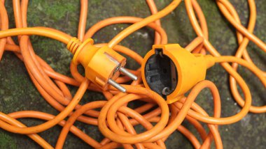 Parlak parlak turuncu uzatma kablosu. Yosunlu beton zeminde turuncu kablo