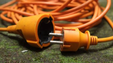 Parlak parlak turuncu uzatma kablosu. Yosunlu beton zeminde turuncu kablo