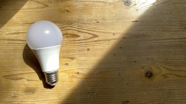 Tahta masada ampul var. Güneş ışığı bir el fenerinin ışığına benzer. İş yaratıcılığı ve ampulle ilgili ilham kavramları. - Evet. Başarı için motivasyon. Büyük fikirler düşün.