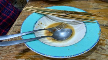 close up view of a knife and fork with a spoon and a white plate