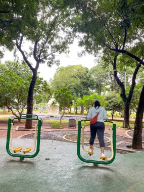 Kadın parkta egzersiz malzemesi kullanarak egzersiz yapıyor. Kız dışarıda egzersiz yapıyor.