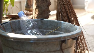 Geri dönüşüm kutusunda süpürge sopası ve ağaç gövdesi olan şişe plastik atığı, ayrı atık toplama konsepti, geri dönüşüm kutusunda plastik şişe, atık yönetimi konsepti.