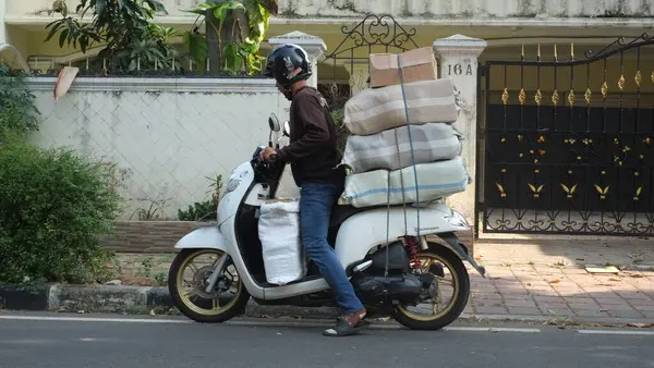 Motosikletli gezintiler ve konut alanına aşırı yüklü bir scooter park etmek. Kuryelerle mal taşımak ve teslimat yapmak için motosiklet kullanımı Endonezya 'da yaygındır..