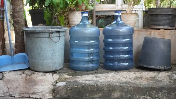 Plastik atık eşyalar, geri dönüştürülmüş eşyalar, boş su galonları, plastik ve kağıt kovalar çevreyi kurtarmak için. Yeşil ağaç arka planı. Çevresel tasarruf kavramı.