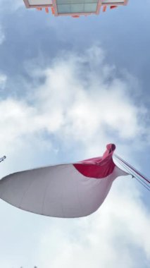 Endonezya Bayrağı 'nın rüzgarda sallanışının dikey videosu, Gökyüzü ve Güneş Arkaplanı. Yoğun güneş ışığı ve ışıltısı, bayrak direği perspektifine bakıyor. 