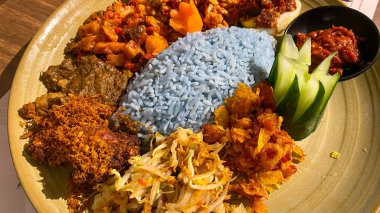 Mavi pirinç, doğal olarak Kelebek Bezelye Çiçeği ile renklendirilmiş, hindistan cevizi sütü ve pandan yapraklarıyla pişirilmiş, çeşitli mezeler ile servis edilmiş kızarmış tavuk, Tempeh, Tofu