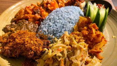 Mavi pirinç, doğal olarak Kelebek Bezelye Çiçeği ile renklendirilmiş, hindistan cevizi sütü ve pandan yapraklarıyla pişirilmiş, çeşitli mezeler ile servis edilmiş kızarmış tavuk, Tempeh, Tofu