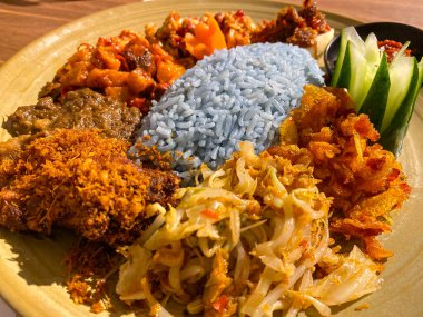 Mavi pirinç, doğal olarak Kelebek Bezelye Çiçeği ile renklendirilmiş, hindistan cevizi sütü ve pandan yapraklarıyla pişirilmiş, çeşitli mezeler ile servis edilmiş kızarmış tavuk, Tempeh, Tofu