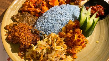 Mavi pirinç, doğal olarak Kelebek Bezelye Çiçeği ile renklendirilmiş, hindistan cevizi sütü ve pandan yapraklarıyla pişirilmiş, çeşitli mezeler ile servis edilmiş kızarmış tavuk, Tempeh, Tofu