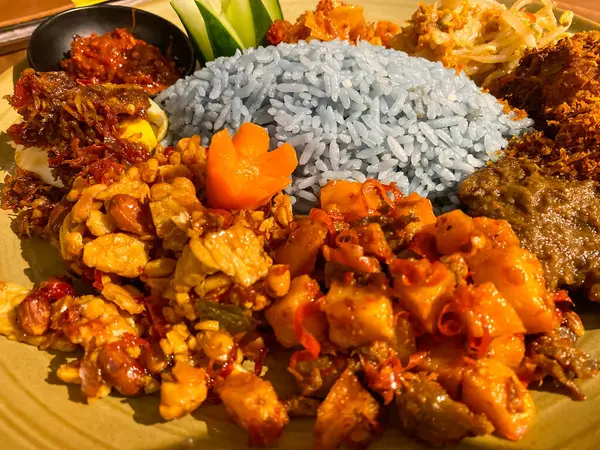 Mavi pirinç, doğal olarak Kelebek Bezelye Çiçeği ile renklendirilmiş, hindistan cevizi sütü ve pandan yapraklarıyla pişirilmiş, çeşitli mezeler ile servis edilmiş kızarmış tavuk, Tempeh, Tofu