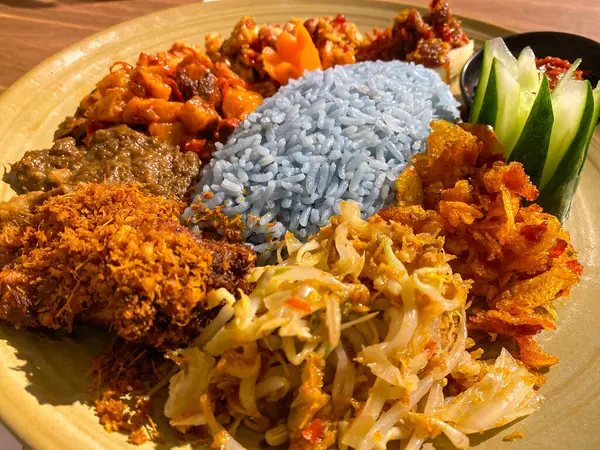 Mavi pirinç, doğal olarak Kelebek Bezelye Çiçeği ile renklendirilmiş, hindistan cevizi sütü ve pandan yapraklarıyla pişirilmiş, çeşitli mezeler ile servis edilmiş kızarmış tavuk, Tempeh, Tofu