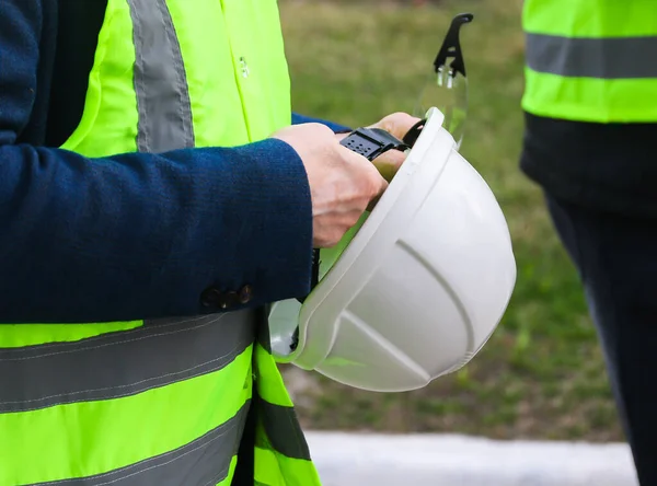 An oil company worker holds a hard hat in his hands