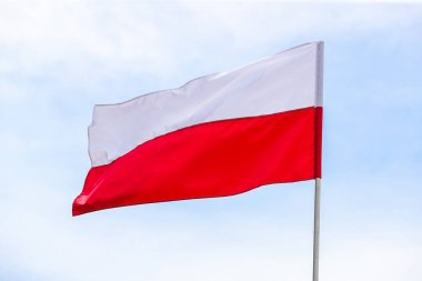 Gündüz vakti, mavi gökyüzünün arka planında Polonya 'nın ulusal bayrağı